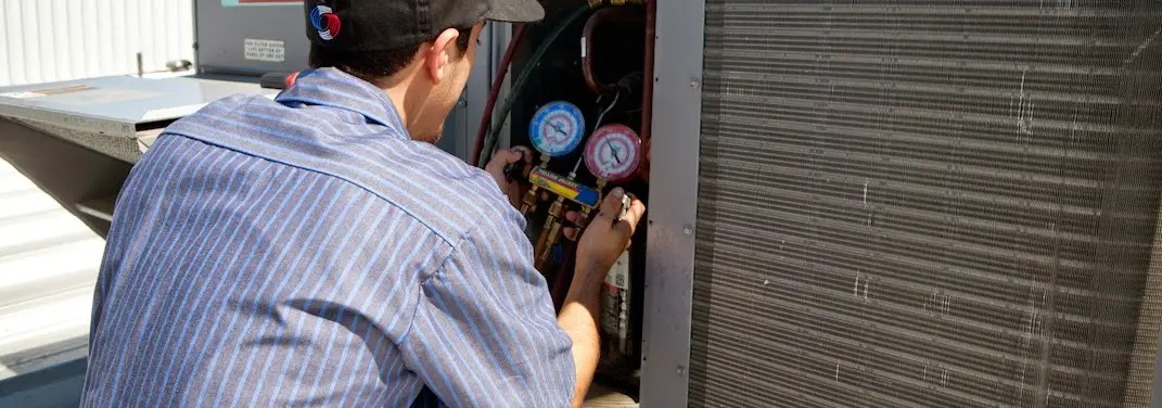HVAC technician servicing a condenser unit in Monaca